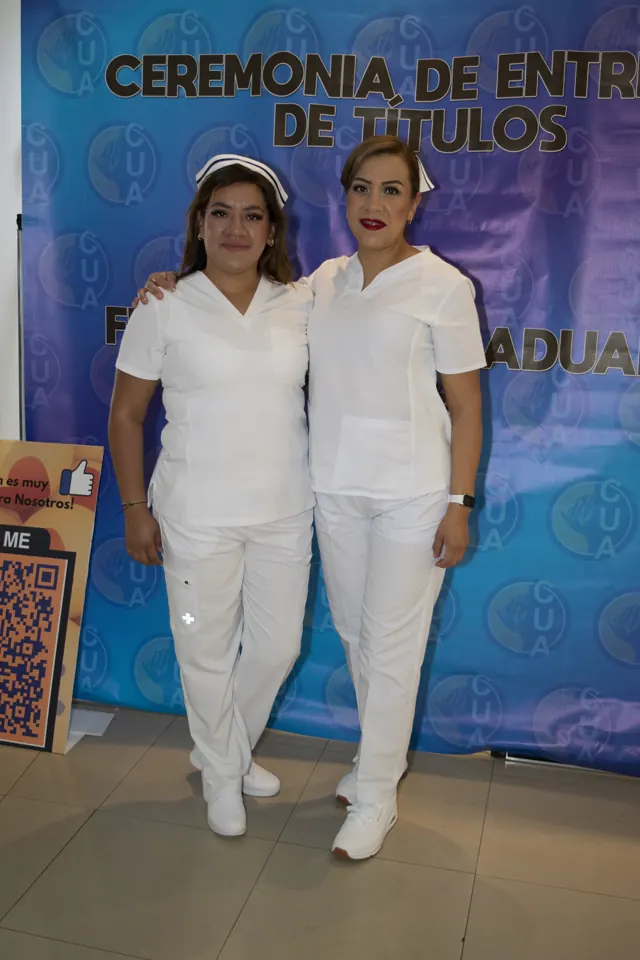 Dos participantes con uniformes blancos posan juntas. Graduación del 7 de julio de 2025.