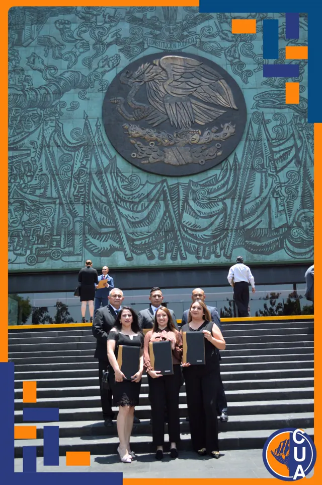 Grupo de egresados y acompañantes posa con sus carpetas de titulación frente a un gran mural.