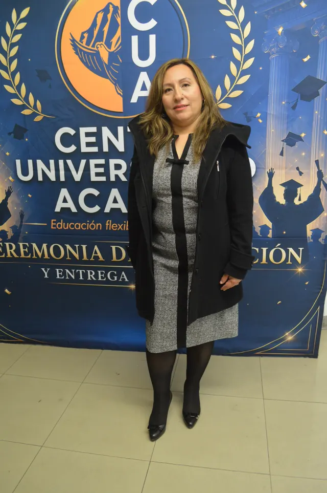 Participante con vestido gris y saco negro posa frente al logotipo del Centro Universitario Acacias.