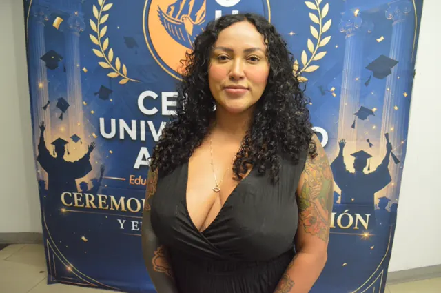 Participante de cabello rizado y vestido negro posa ante el fondo institucional de Acacias.