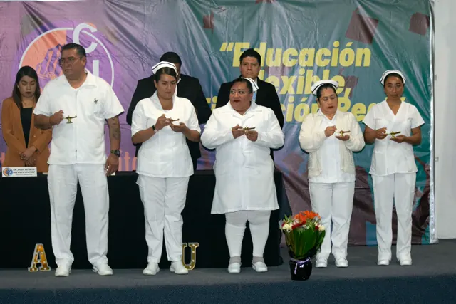 Grupo de enfermería participa en la ceremonia con velas en el escenario. Graduación del 14 de junio de 2025.